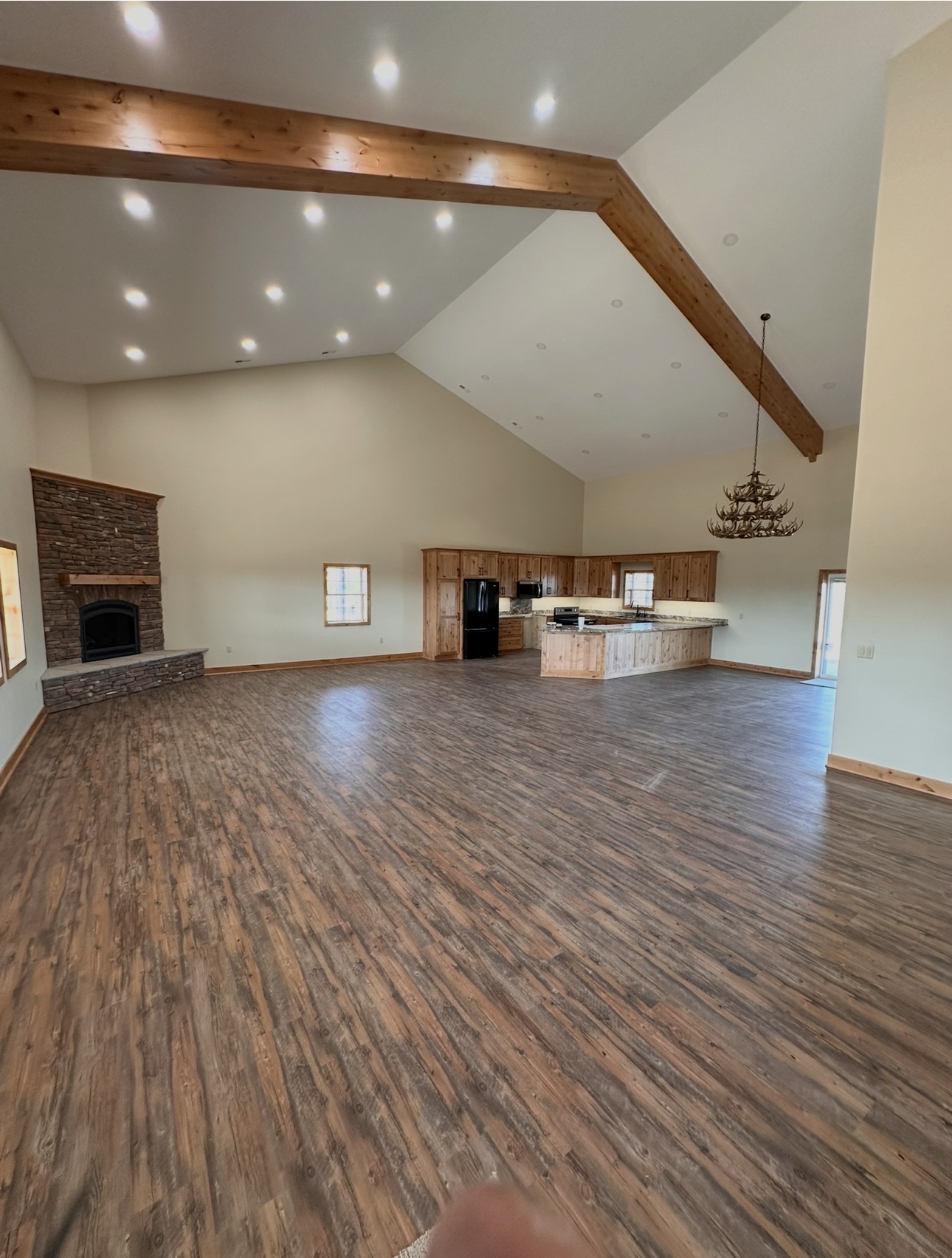 Vaulted open living area with exposed wood beams and a stone fireplace