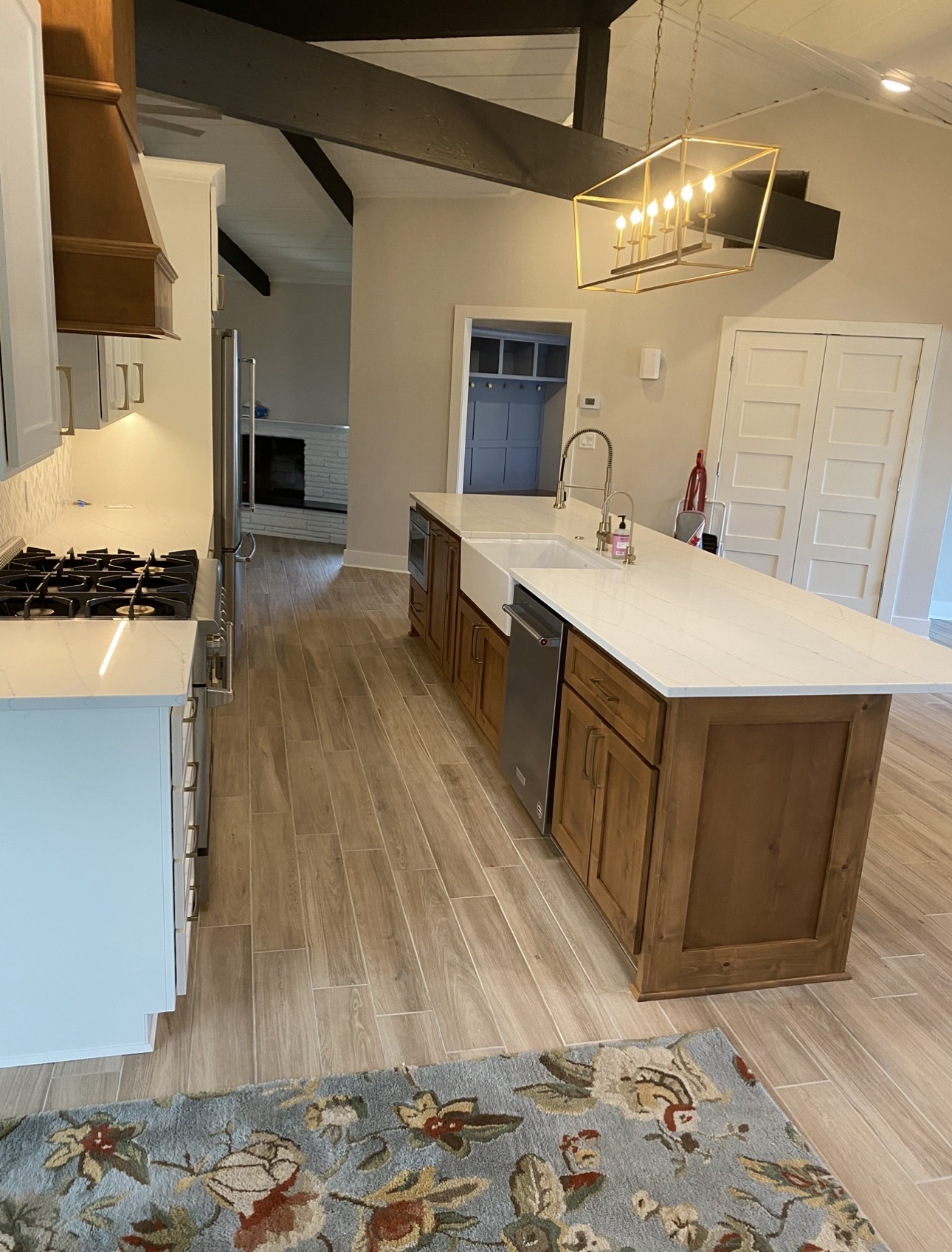 Natural wood kitchen island with white countertops, white cabinets, and a brass pendant light