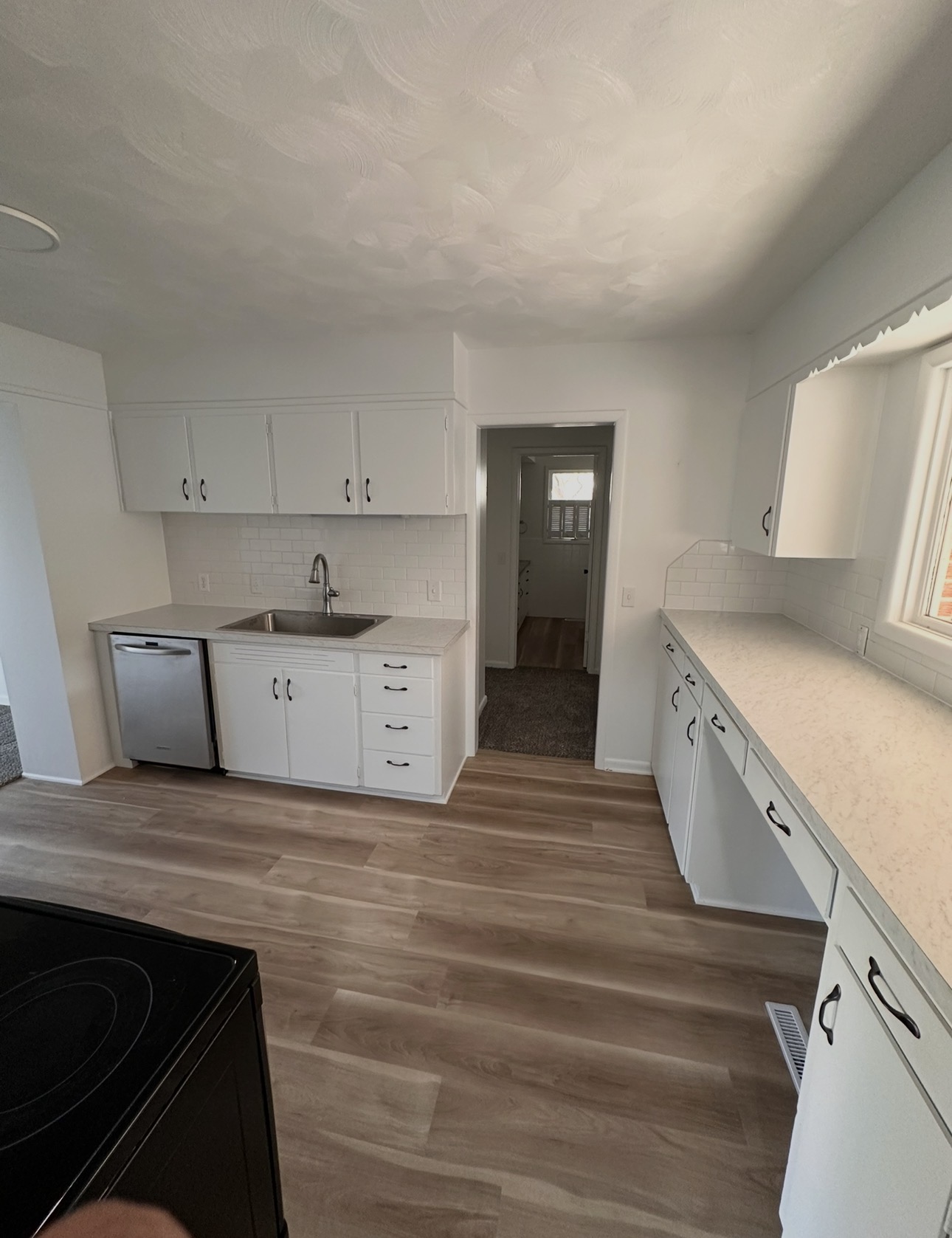 Bright kitchen with white cabinetry, pale countertops, and wood-look flooring
