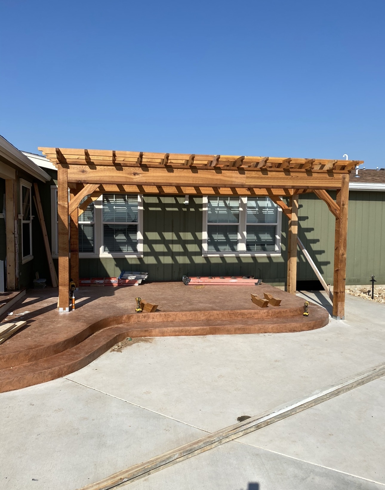 Wood pergola over an outdoor seating area surrounded by a concrete patio