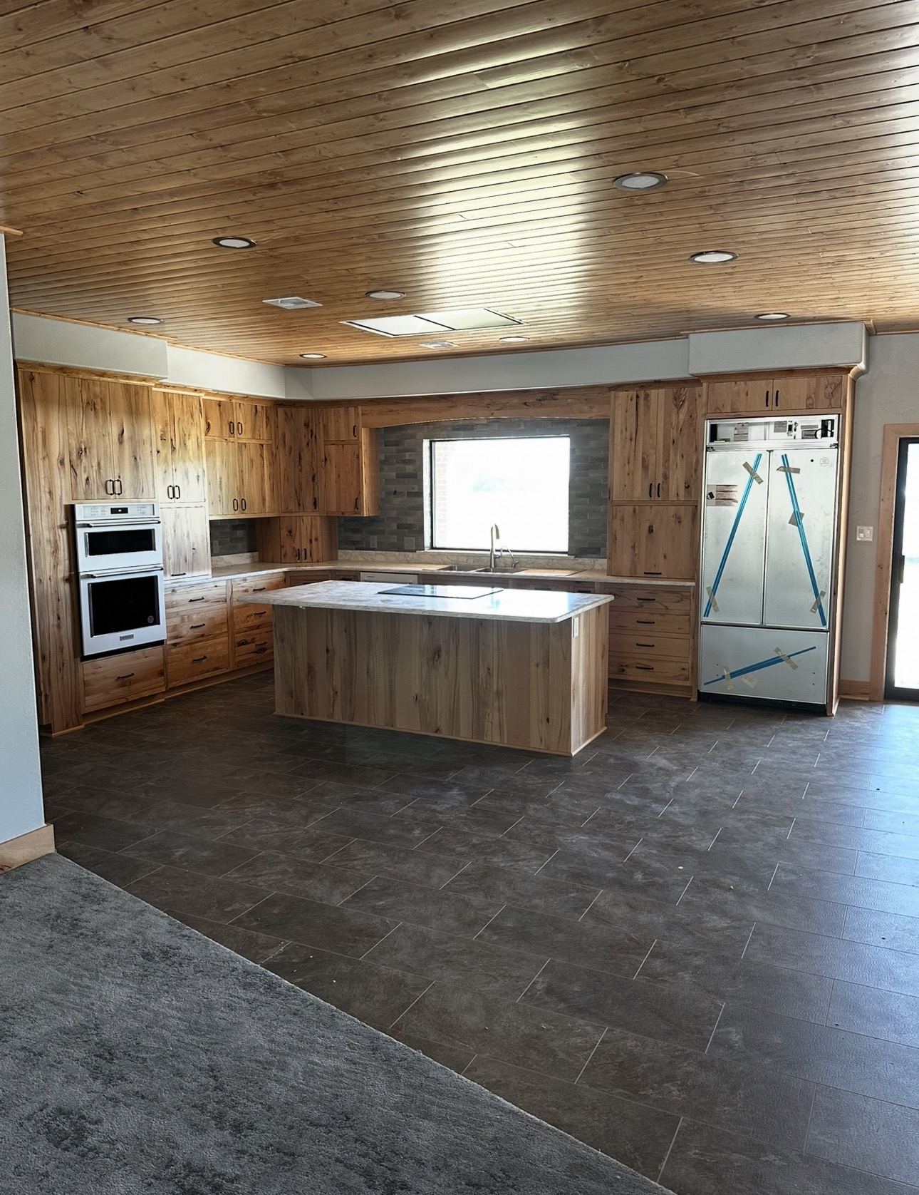 Kitchen project with wood-plank walls and ceiling, wood cabinetry, and an island